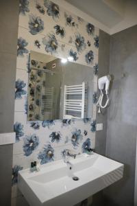 Farina rooms and apartments في San Nicola La Strada: حمام به حوض غسيل ومرآة مزينة بأزهار زرقاء