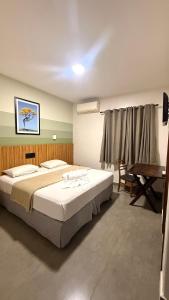 een slaapkamer met een groot bed en een bureau bij Limeira Plaza Hotel in Limeira