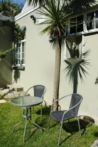 two chairs and a table and a palm tree at Villa Barry in Hout Bay