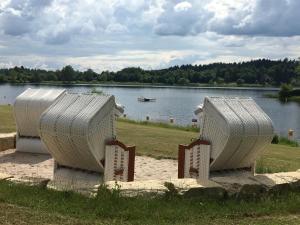 due sedie bianche sedute in un campo vicino a un lago di Natur, Kultur und Wandern a Losheim