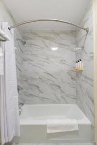 baño con bañera blanca y pared de mármol en The Prime Suites, Vallejo - Napa Valley and Six Flags Discovery Kingdom, en Vallejo