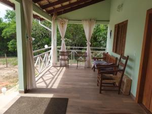 eine Veranda eines Hauses mit Stühlen und einem Tisch in der Unterkunft Quintal dos Pinheiros in Pirenópolis