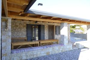 un banc en bois assis sur le côté du bâtiment dans l'établissement AMPELOPETRA - Slow Country Living, à Ioannina