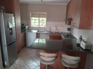 een keuken met een wastafel en een aanrecht met 2 krukken bij Nested at L&MX in Centurion