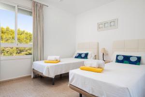 two beds in a white room with a window at Villa El Olivo in Pollença +14 photos