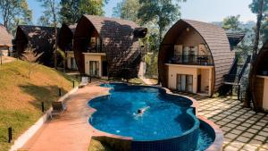 eine Person, die in einem Pool vor einem Haus schwimmt in der Unterkunft Golf Valley Luxury Resort Wayanad in Vythiri