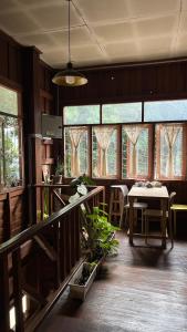 ein Esszimmer mit einem Tisch und einigen Fenstern in der Unterkunft Yorsong Hostel Pai in Kampong Huaibū