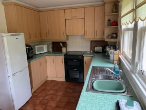 a small kitchen with a sink and a refrigerator at Glenerne 3 bedroom Cottage in Elgin