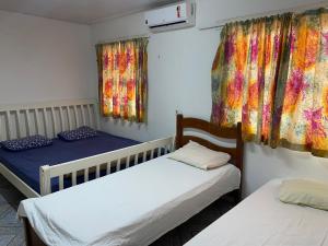 2 bedden in een kamer met kleurrijke gordijnen bij Casa no cumbuco in Caucaia