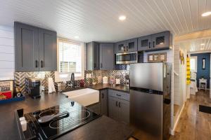 a kitchen with black cabinets and a stainless steel refrigerator at Hagrid's Hut - Harry Potter Riverfront Experience in New Richmond