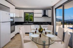 een keuken met een glazen tafel en witte stoelen bij Villa Vala in Kalkan