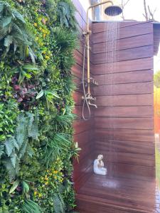 a shower in a garden with a cat sitting on the ground at Caprice Gruissanais Spa - T2 plage des chalets in Gruissan
