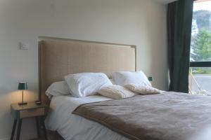 een bed met witte lakens en kussens naast een raam bij Kj Homes in Prénatier