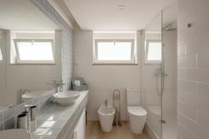 a white bathroom with two sinks and two toilets at Cascais Bay Terrace I in Cascais