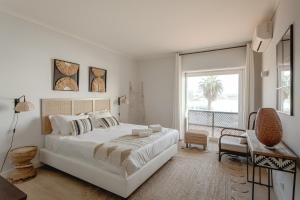 a white bedroom with a large bed and a balcony at Cascais Bay Terrace I in Cascais