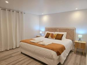 a white bedroom with a large bed with two tables at Aconchego da Vila in Castelo de Vide
