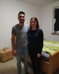 Doppelbett für Zwei في دينسلاكن: رجل وامرأه واقفين بجانب سرير