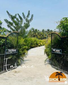 una puerta que conduce a una playa con palmeras en Yashokiran Farmstay, en Borlai