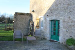 two chairs and a green door in a stone building at Domaine Des Piéris - Chambres d'Hôtes in Grandcamp-Maisy