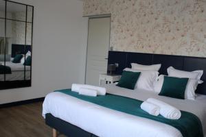 a bedroom with a large bed with green and white pillows at Domaine Des Piéris - Chambres d'Hôtes in Grandcamp-Maisy +23 photos