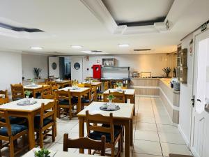 a restaurant with tables and chairs and a kitchen at Pousada Ruppenthal in Canela