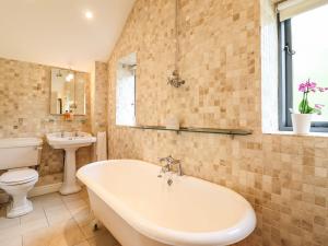 a bathroom with a tub and a toilet and a sink at The Talkhouse Cottage in Caersws +15 photos