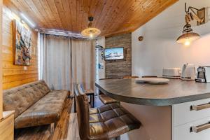 een keuken met een aanrecht en een bar met lederen stoelen bij Cosy 5 persons / Ski In Ski out in Val Thorens +5 foto's