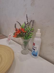 a vase of flowers next to a bottle of medication at Apartman LUX Jelena in Surčin