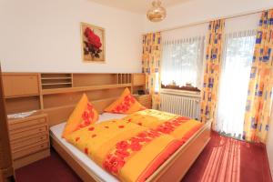 um quarto com uma cama com lençóis laranja e amarelo em Hotel Pension Fernblick em Sankt Andreasberg
