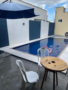 a table and chairs and an umbrella next to a swimming pool at Casa TDM 2 in Macapá