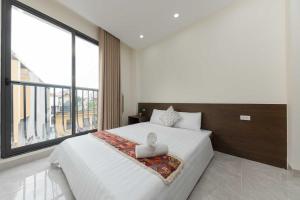 a bedroom with a white bed with a large window at Collection O West Lake Apartment in Hanoi