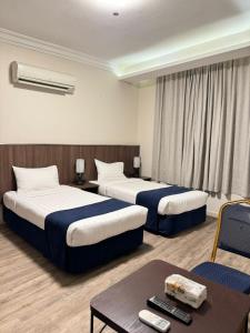 a hotel room with two beds and a table at Hayat Al madinah Hotel فندق حياة المدينة in Al Madinah