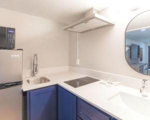 a kitchen with blue cabinets and a sink and a mirror at ECONOMY INN AND SUITES in Tulsa