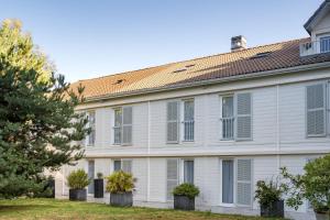 a white building with windows and plants in pots at Best Western Hotel Acadie Paris Nord Villepinte in Tremblay En France