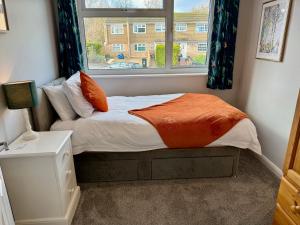 a bedroom with a bed with an orange blanket and a window at Oak View - Spacious 3 Bedroom House near Oxford and the Cotswolds in North Leigh