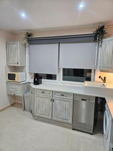 eine Küche mit weißen Schränken und einem großen Fenster in der Unterkunft Casa Las Patas De Los Patos in La Sabinita