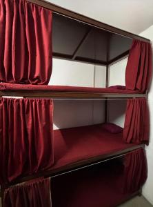 two bunk beds in a room with red curtains at Shivanand Aashray - Near Sangam in Prayagraj
