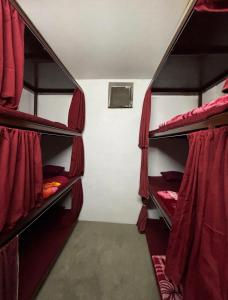 a room with three bunk beds with red curtains at Shivanand Aashray - Near Sangam in Prayagraj