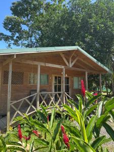 een houten huis met een veranda en bloemen bij Bobinsana INN in Puerto Limón