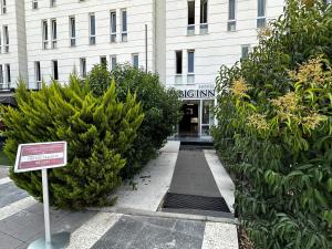 un cartello davanti a un edificio con cespugli di Big Inn Luxury Hotel a Biga