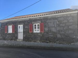 een stenen gebouw met rode luiken op een straat bij Recanto Vital in Achadinha