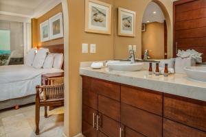 Un baño con dos lavabos y un dormitorio con una cama. en Luxury Beachfront Condo Punta Mita, en Punta Mita