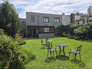 Ein Hof mit vier Stühlen und einem Tisch vor einem Haus in der Unterkunft Posada del Atelier in San Antonio de Areco