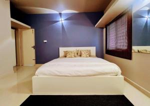 een slaapkamer met een wit bed en een paarse muur bij Eden Green Nest in Bangalore