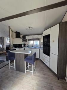 eine Küche mit weißen Geräten und blauen Stühlen in der Unterkunft Rody's Cosy Corner in Crowle