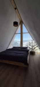 un letto in una camera con una grande finestra di Wild Hill Apuseni a Gârda de Sus