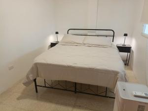 Un dormitorio con una cama con dos mesitas de noche y dos lámparas. en Apartamento Renovado a 5 Minutos del Centro Comercial Sambil Candelaria en Caracas, en Caracas 21 fotos más