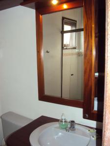 a bathroom with a sink and a mirror and a toilet at Pousada Refugio Port Sahy in Barra do Sahy