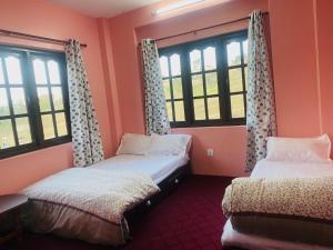 Dos camas en una habitación con ventanas. en Bhaktapur Yog Homestay, en Bhaktapur