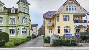 una fila di case gialle e verdi su una strada di FeWo Valencia Am Rosenhof - 5 Sterne DTV a Kühlungsborn